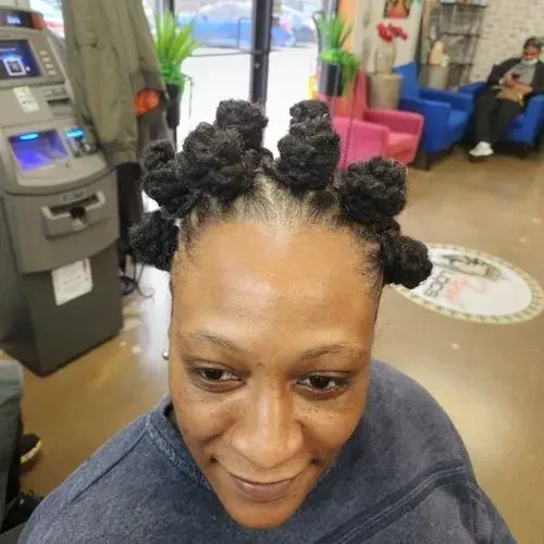 A woman with dreadlocks is smiling in front of an atm machine.