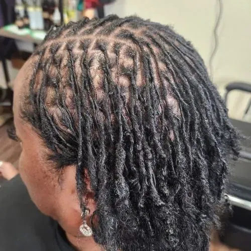 A woman with dreadlocks is sitting in a chair in a salon.