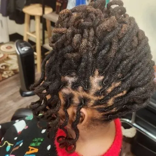 A woman is sitting in a chair with dreadlocks in her hair.