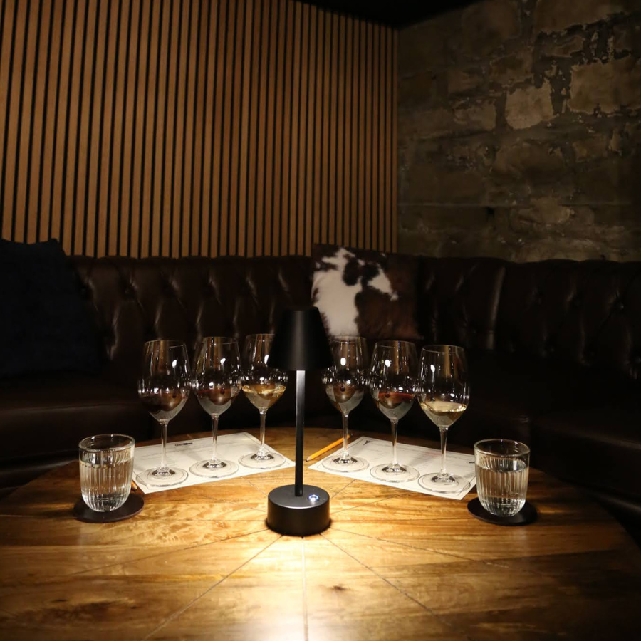 Cozy restaurant table set with wine glasses and water glasses around a small centerpiece on a wooden table