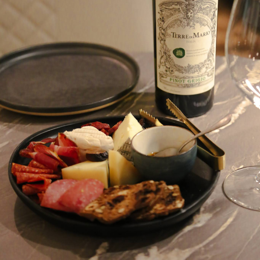 Cheese and charcuterie platter with crackers beside a bottle of wine on a table