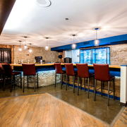 Modern bar interior with stone counter, red stools, and blue-lit windows