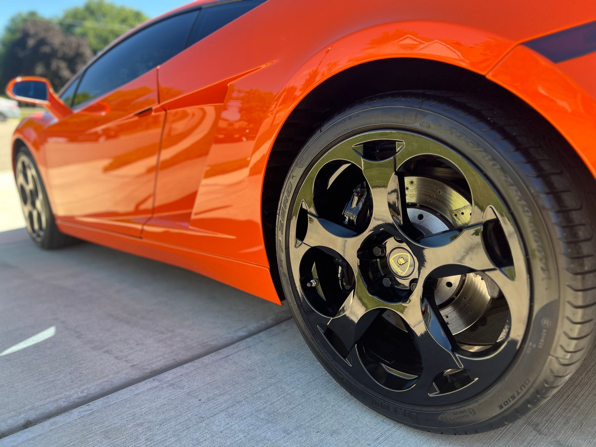 Bright orange Lamborghini with black wheels parked on a driveway.