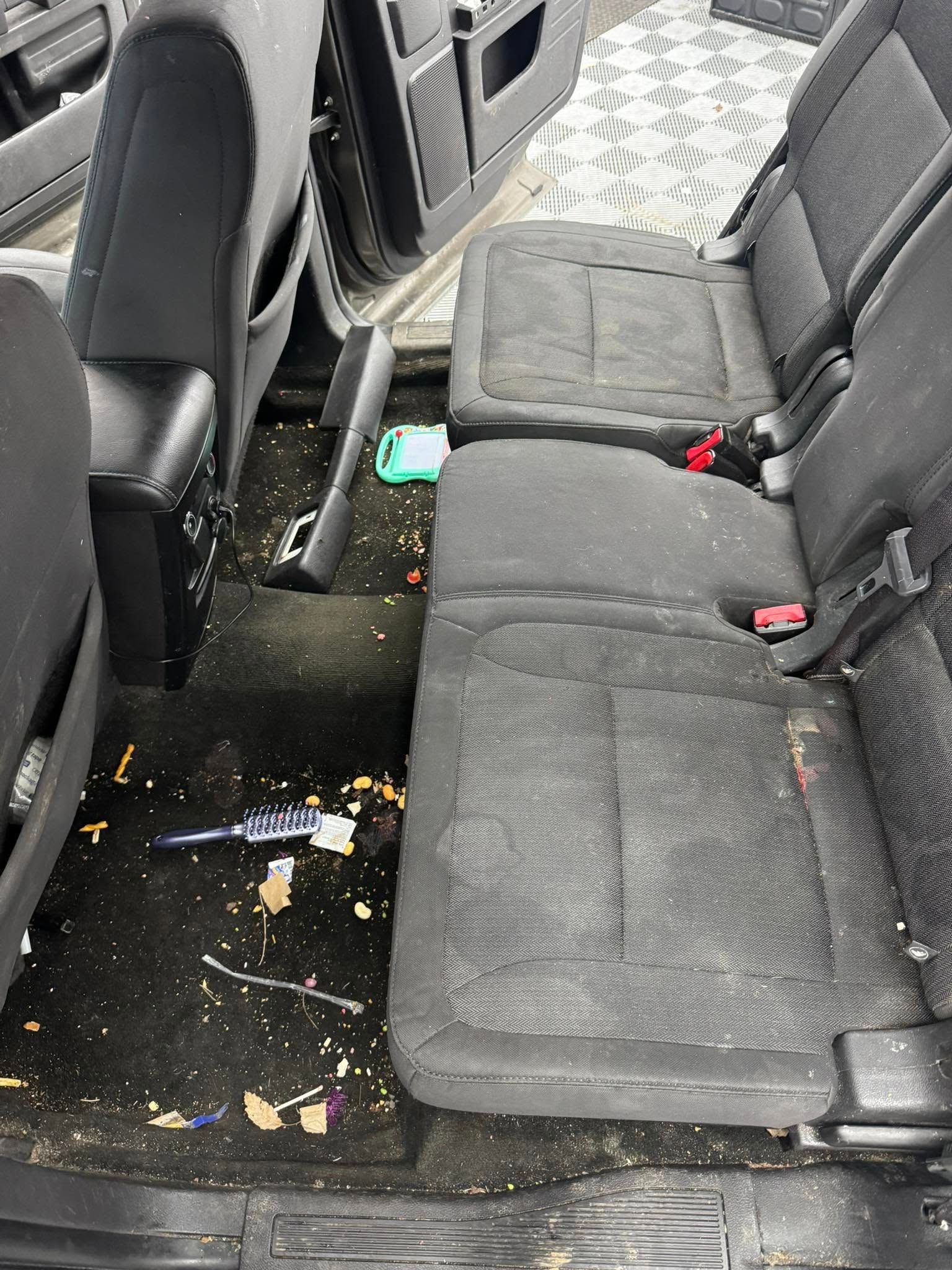 A dirty car with a vacuum cleaner in the back seat.