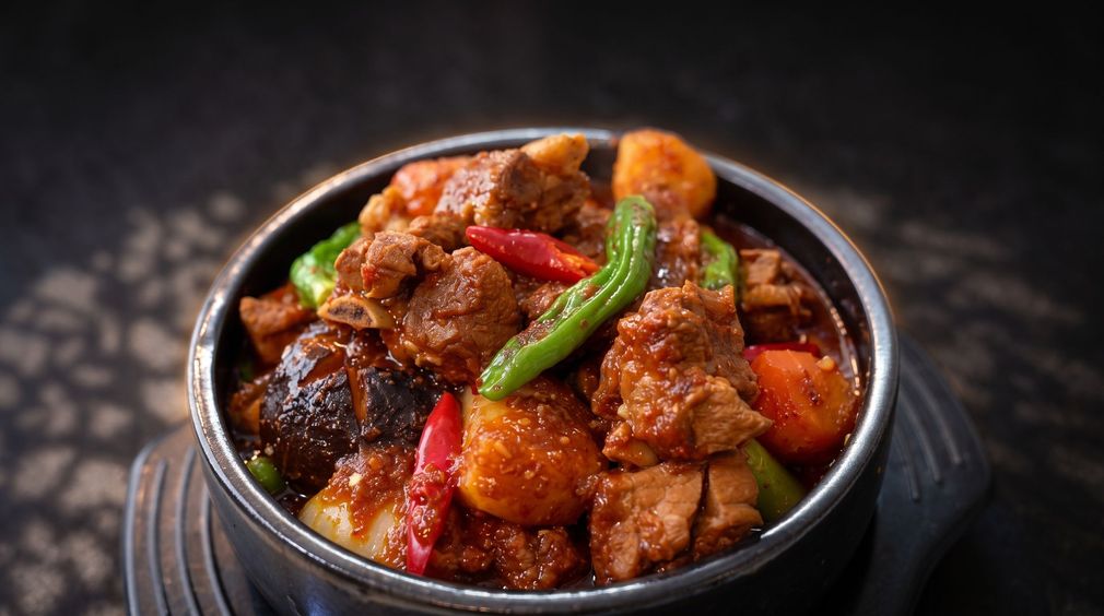 Bowl of spicy stir-fried meat and vegetables with green chilies and red peppers