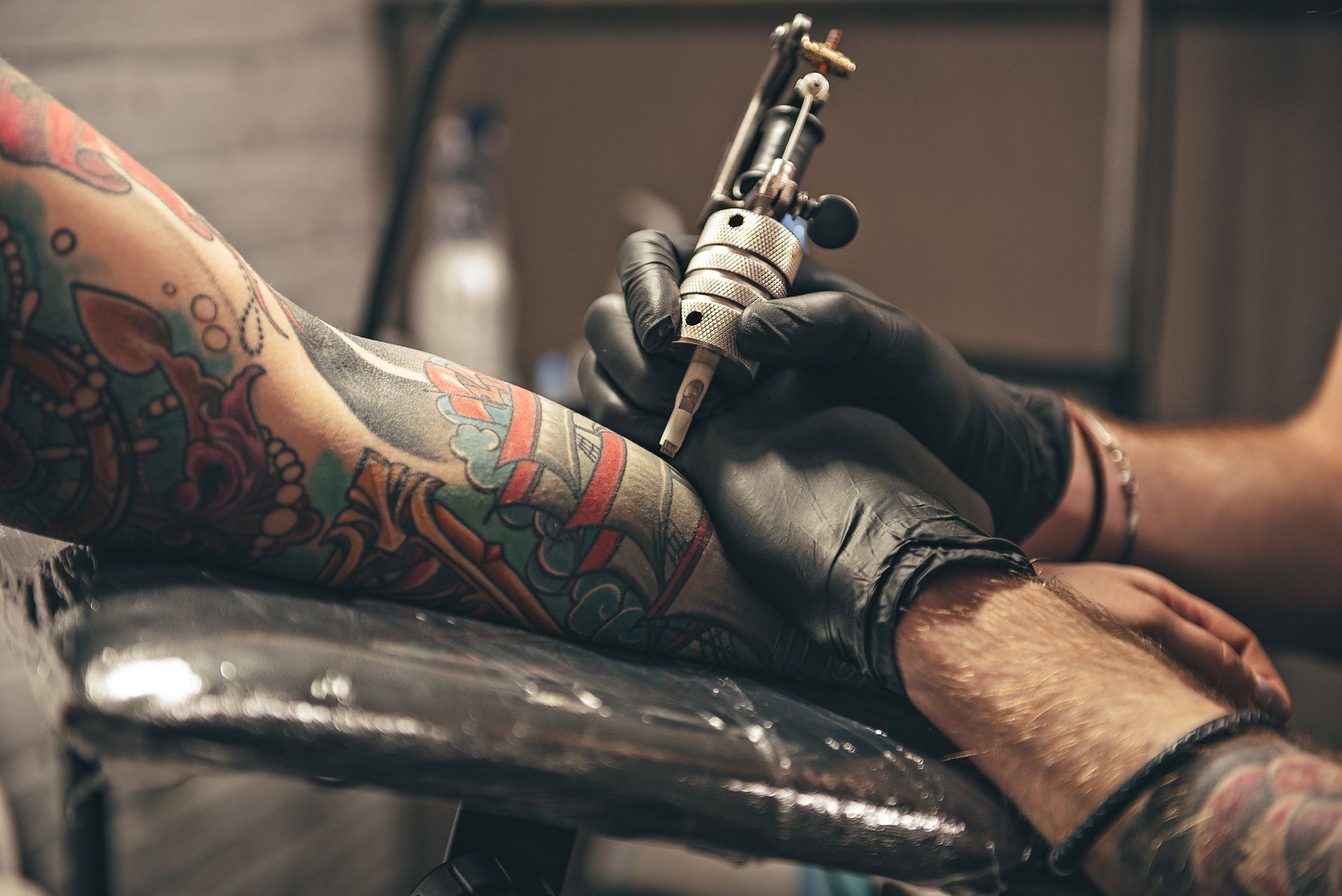 close up tattoo machine. Man creating picture on hand with it in salon.
