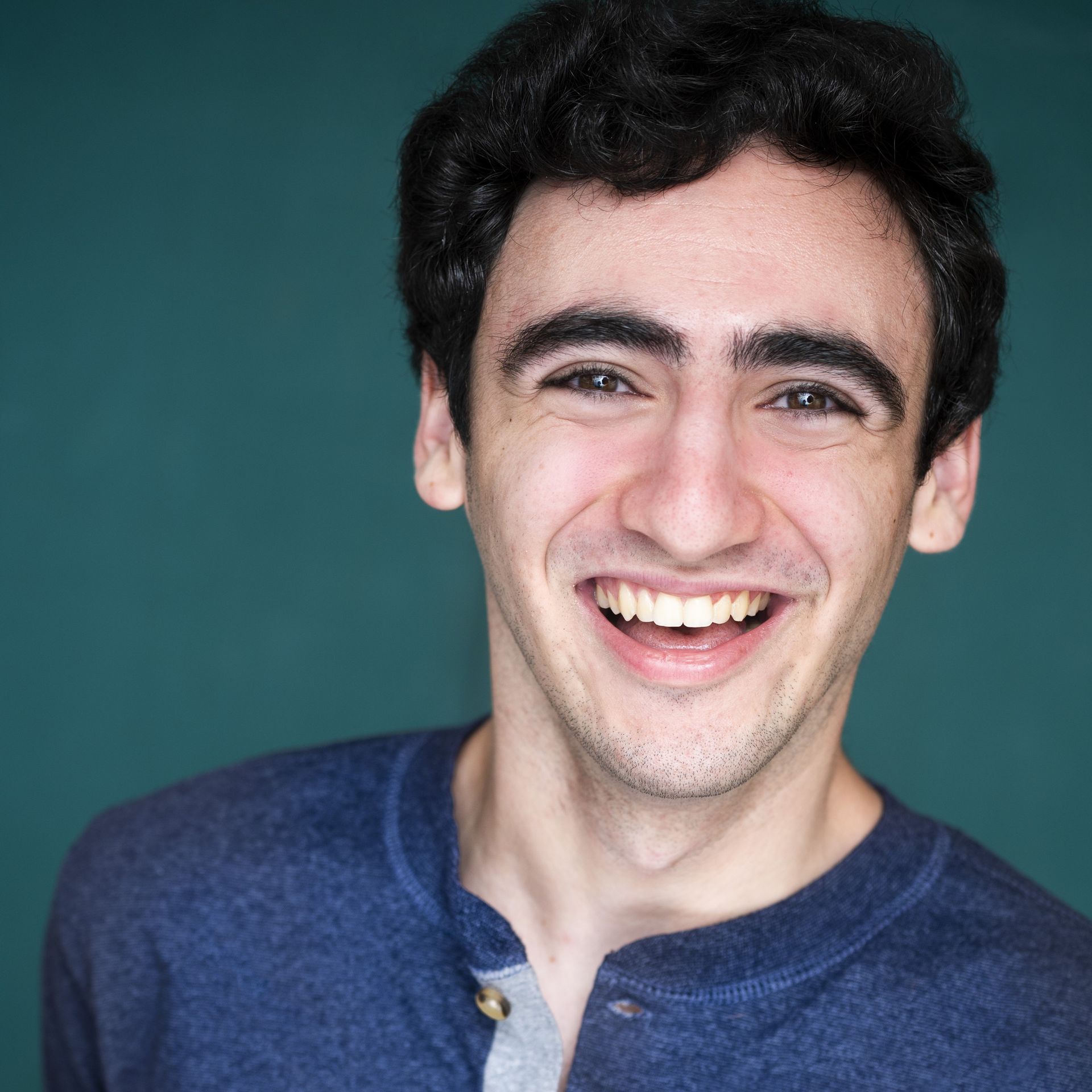 Smiling person in a blue shirt against a teal background