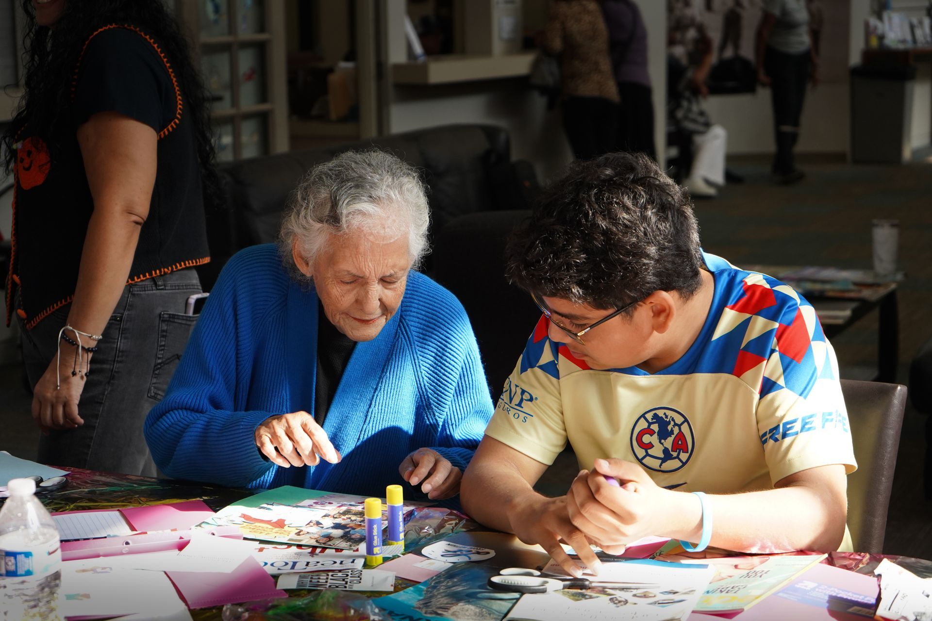 Woman and young person working on a puzzle at a table indoors.