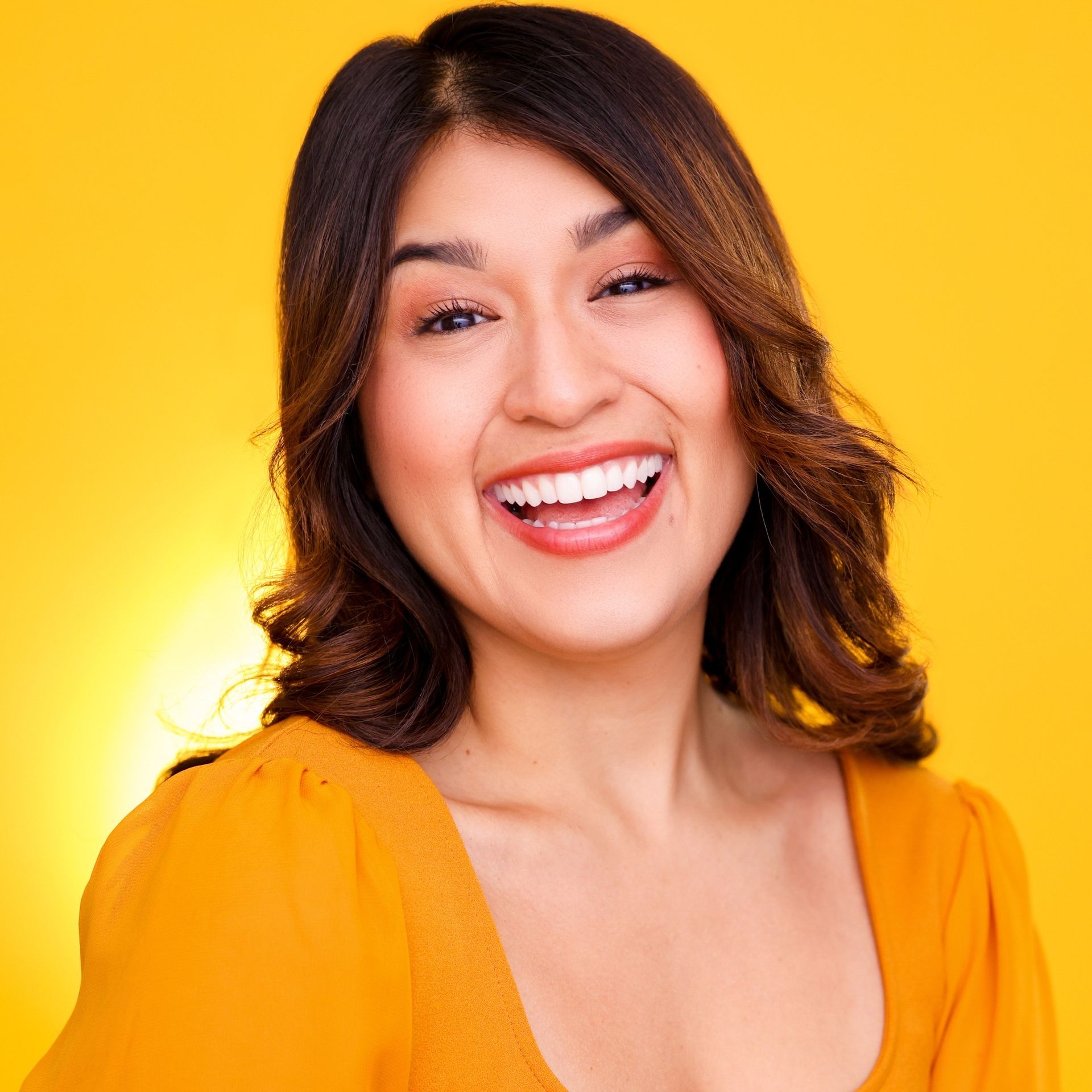 Smiling woman in a bright yellow top against a yellow background