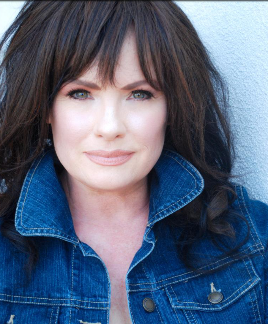 Close-up portrait of a woman with dark hair wearing a blue denim jacket against a light background