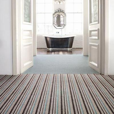 Striped carpet leading to bathroom with bathtub in background