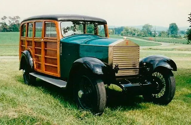 an old woody station wagon is parked in a grassy field .
