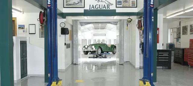 a green jaguar is sitting on a lift in a garage .