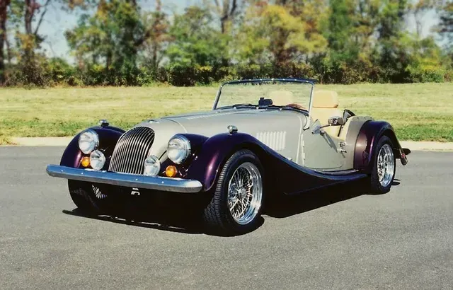 a purple and silver sports car is parked on the side of the road .