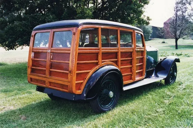 a wooden wagon is parked in a grassy field