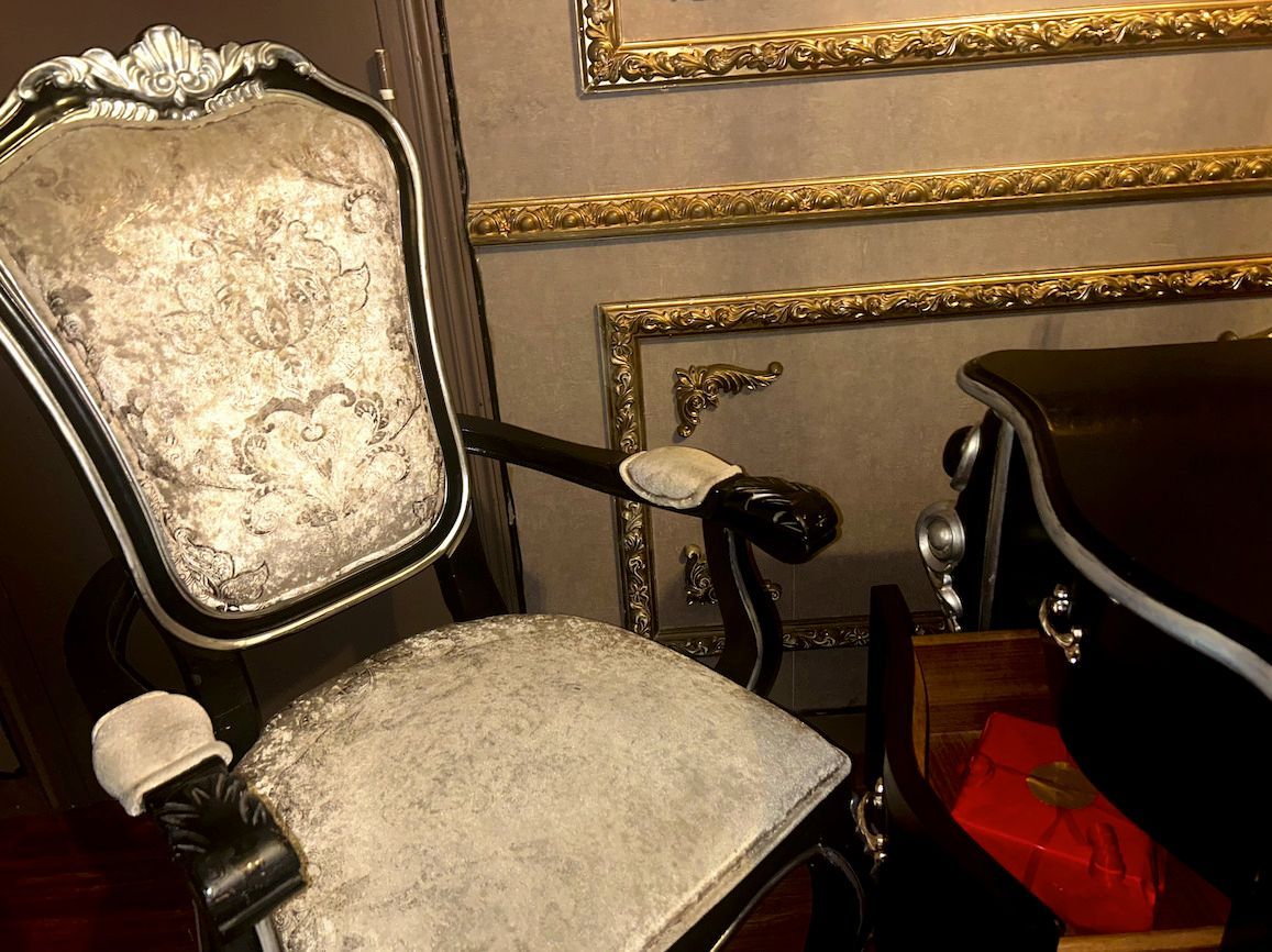 Une chaise est assise devant un mur avec des bordures dorées