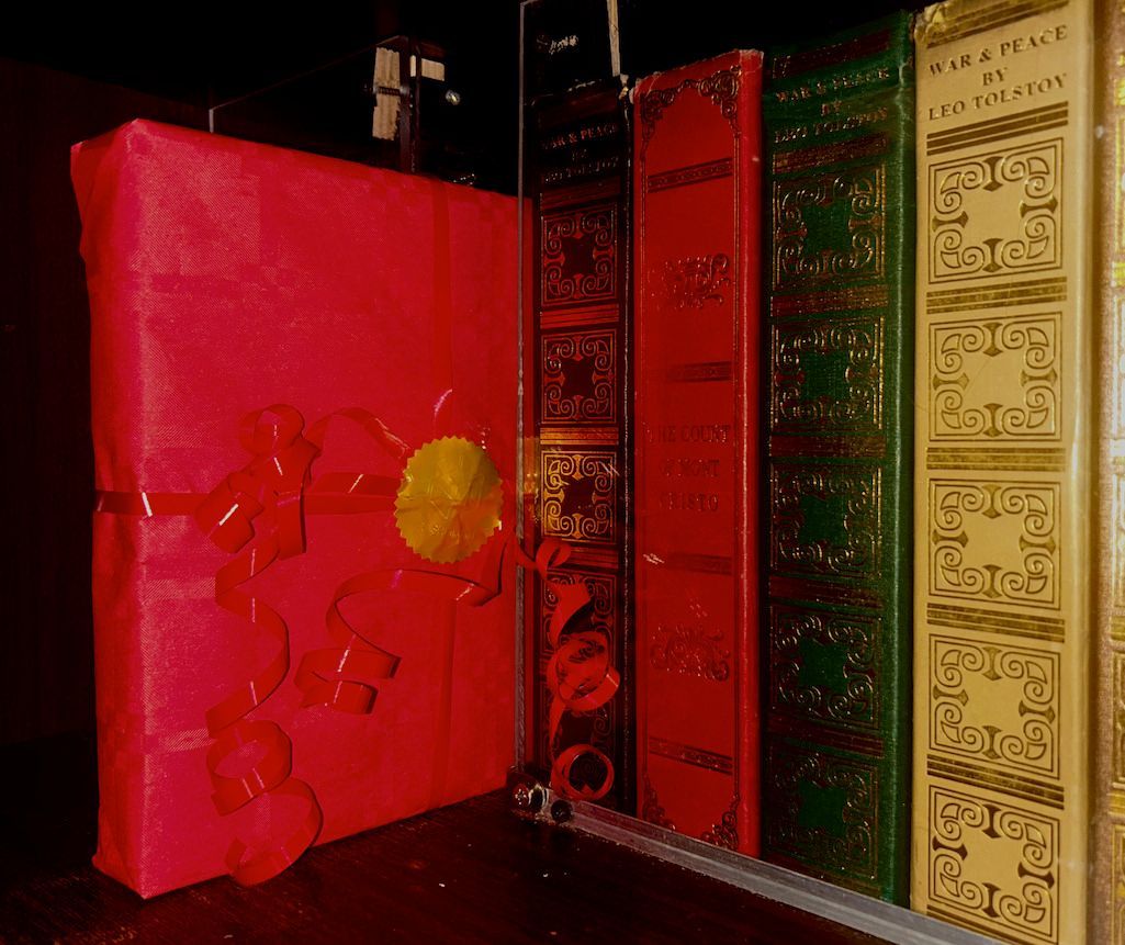Un livre rouge avec une fleur jaune dessus est sur une étagère avec d'autres livres
