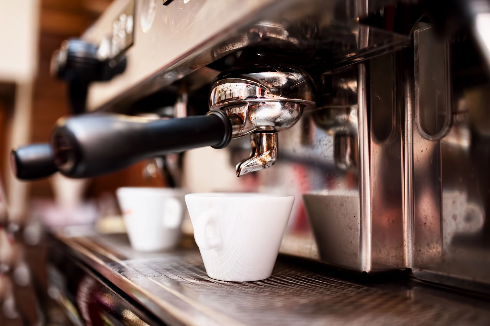 Macchina per caffè espresso che prepara il caffè in due tazze bianche.