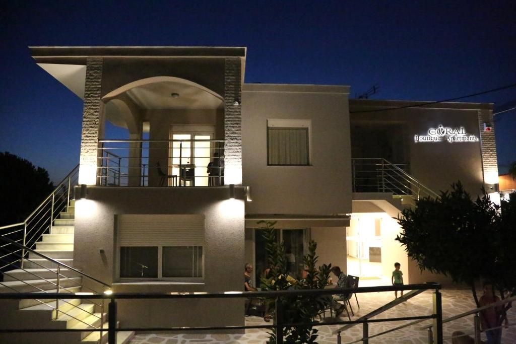 Two-story building exterior at night, lit with outdoor lights. People are visible on balcony and below.