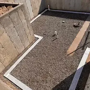 Passive radon system roughed in before the slab pour: clean gravel base, sealed perimeter expansion joint, and vent pipe stub-ups set in the foundation of a new Utah home