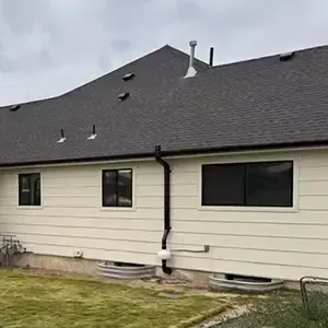 Radon mitigation system installed on a white modern farmhouse in Utah, with the vent pipe run flush against the siding and painted to blend in