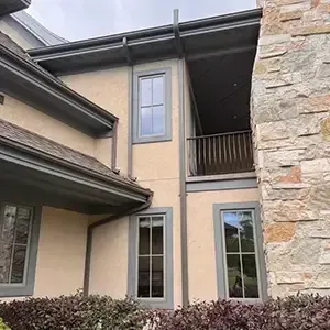 Radon mitigation system installed on a white modern farmhouse in Utah, with the vent pipe run flush against the siding and painted to blend in