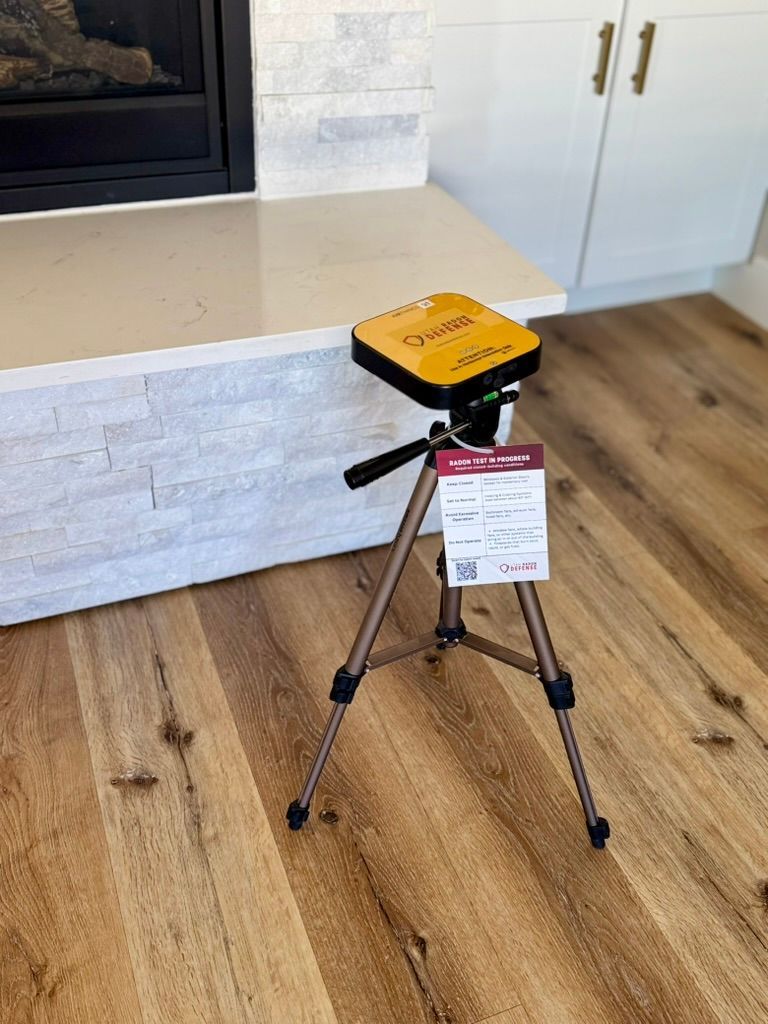 Yellow device on a tripod in a modern kitchen, beside a white island with wood flooring.