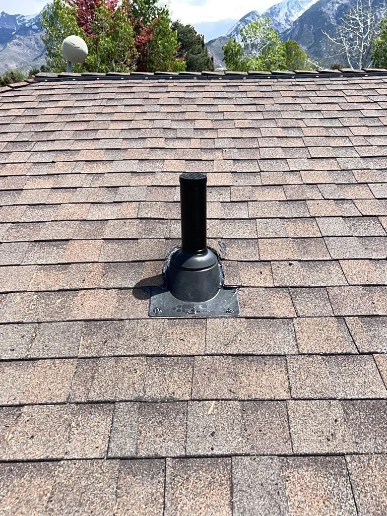 Rooftop vent pipe on a shingled roof with mountains in the background