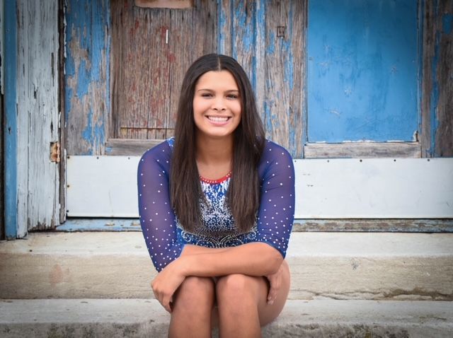 Woman smiling while sitting on steps in front of a blue door