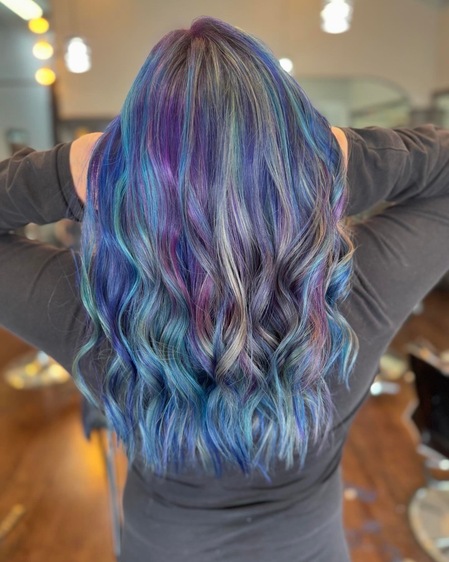 A woman with pink and purple hair is dancing in the dark.