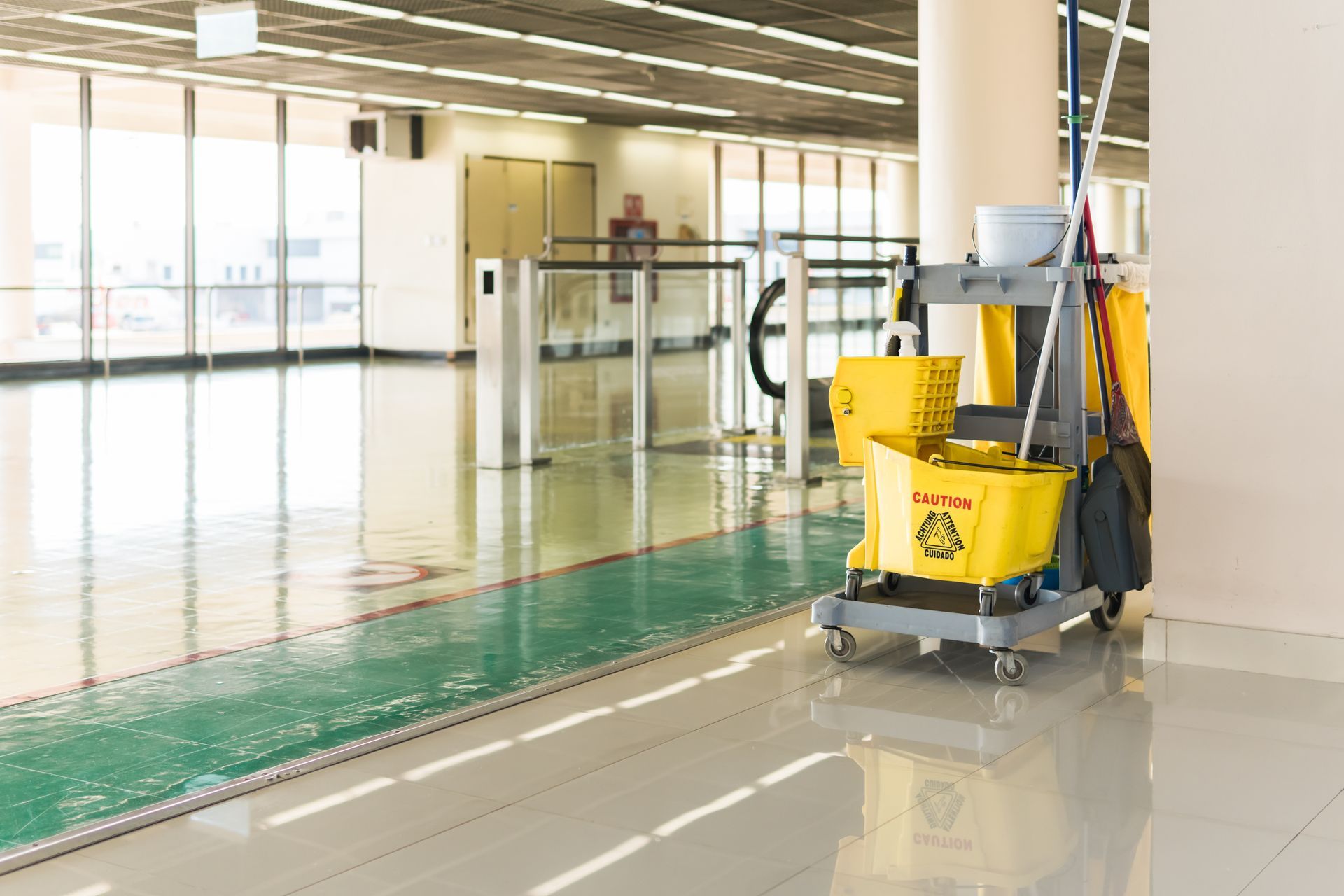 Bright indoor pool area with a cleaning cart and yellow mop buckets on a glossy floor