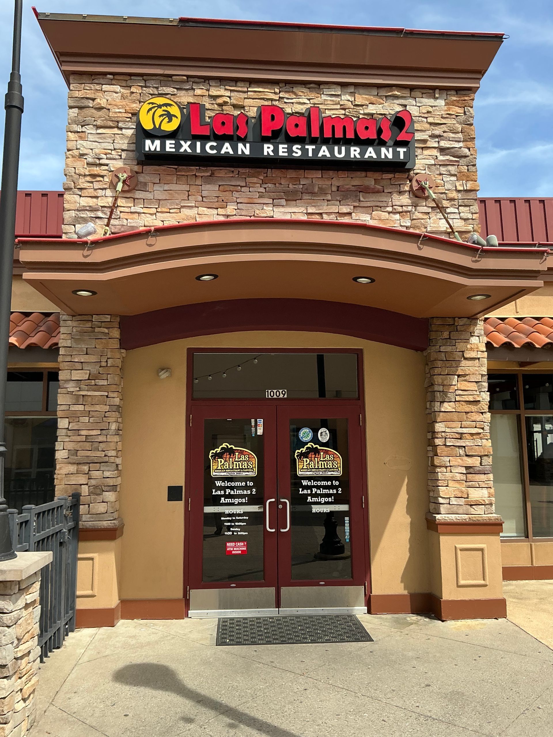 Exterior of Los Palomas Mexican Restaurant with a stone facade and red door.