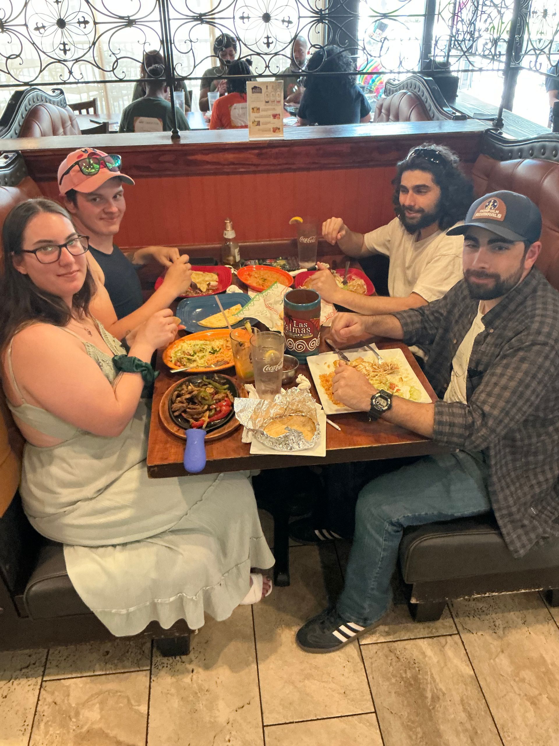 Four people seated at a restaurant table with food, smiling.