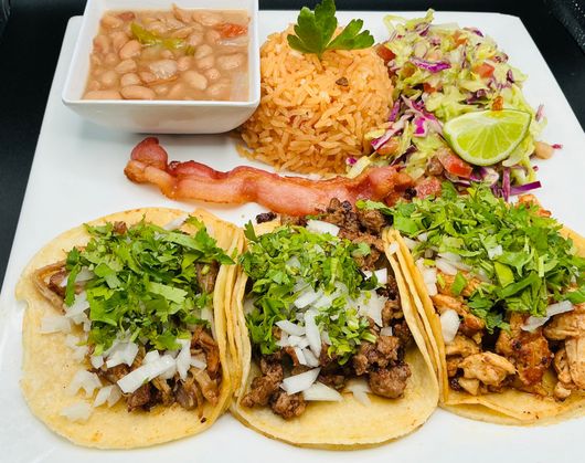Plate of Mexican food: tacos, rice, beans, bacon, and salad.