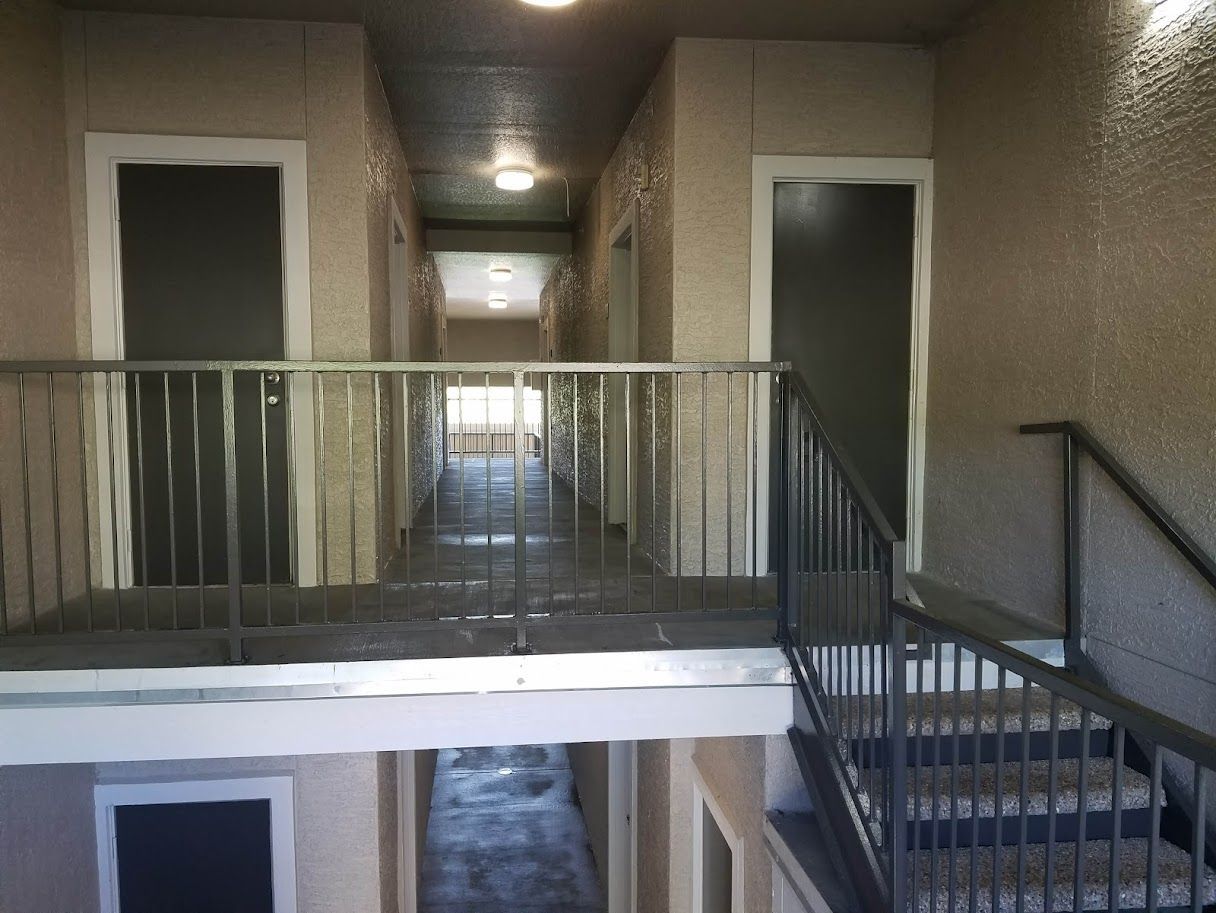 Interior hallway with a balcony railing and stairs leading to an upper level