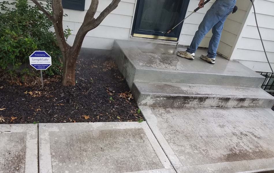 Front porch steps with a concrete landing, tree, and a person standing by the door.
