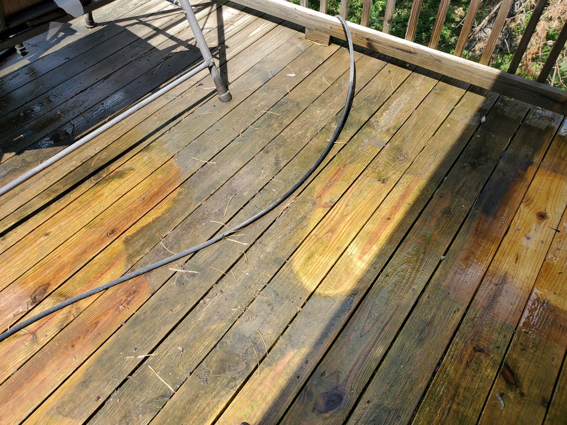 Sunlit weathered wooden deck with curved black railing and shadows