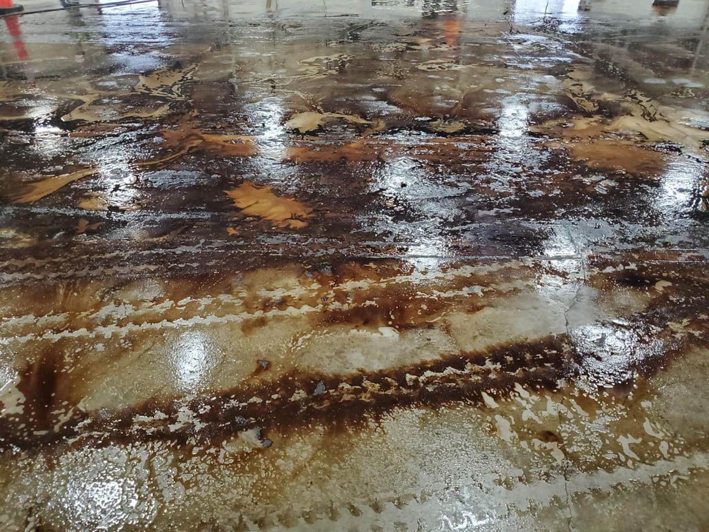 Midway through power washing a warehouse floor that has been oil stained for many years.