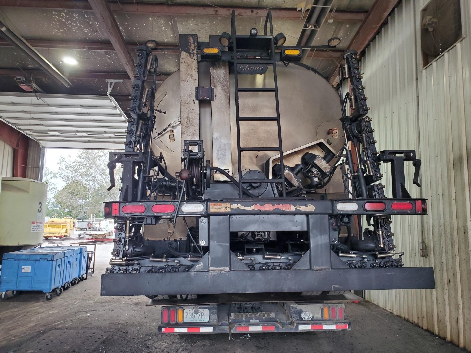 Industrial machine loaded on a trailer inside a warehouse/loading dock.
