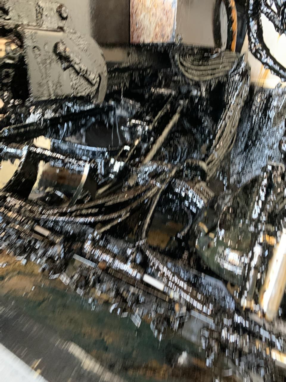 Close-up of a damaged, wet engine compartment with tangled black hoses and metal parts.
