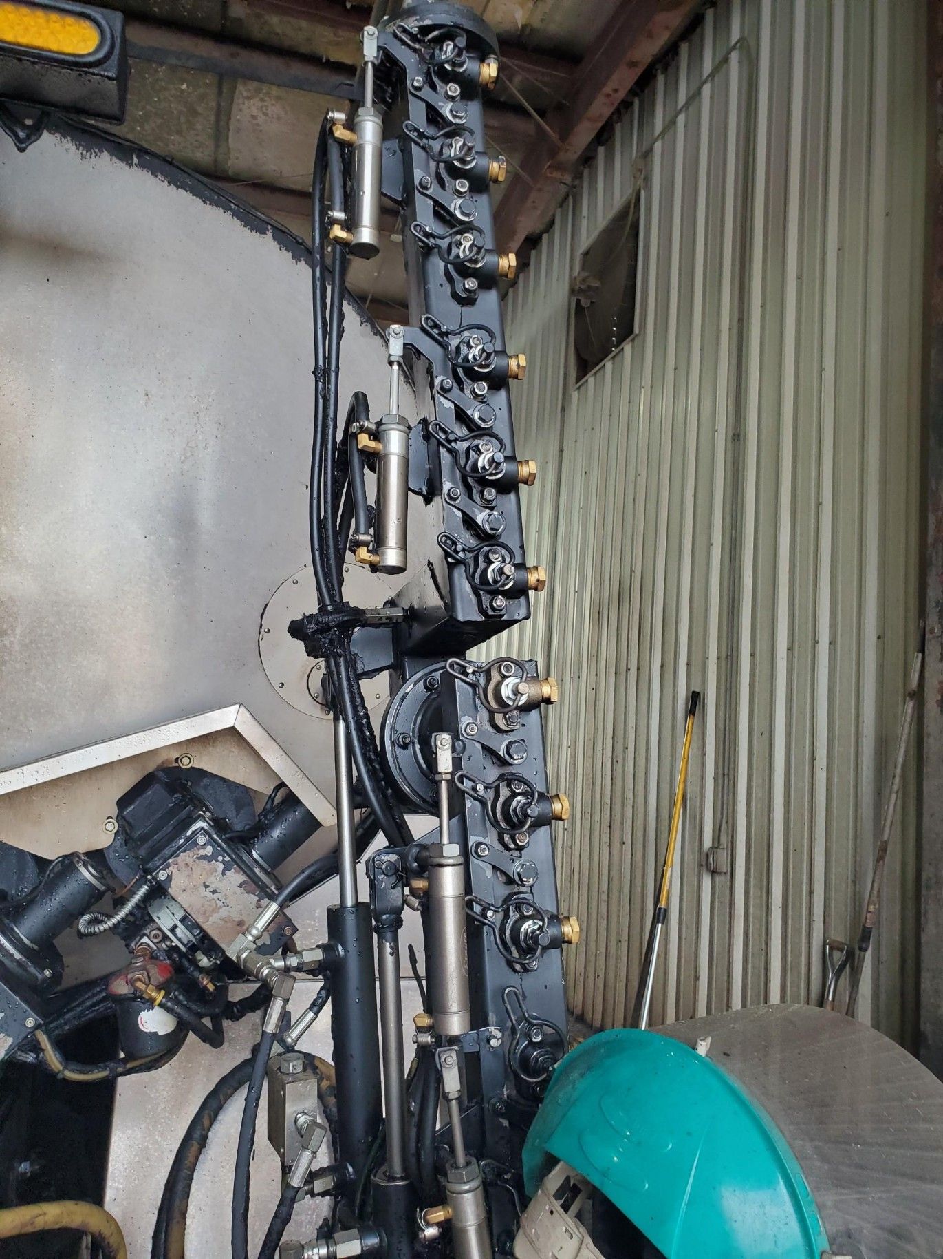 A tall rack of fishing rods and gear stands beside a corrugated wall in a cluttered storage area.