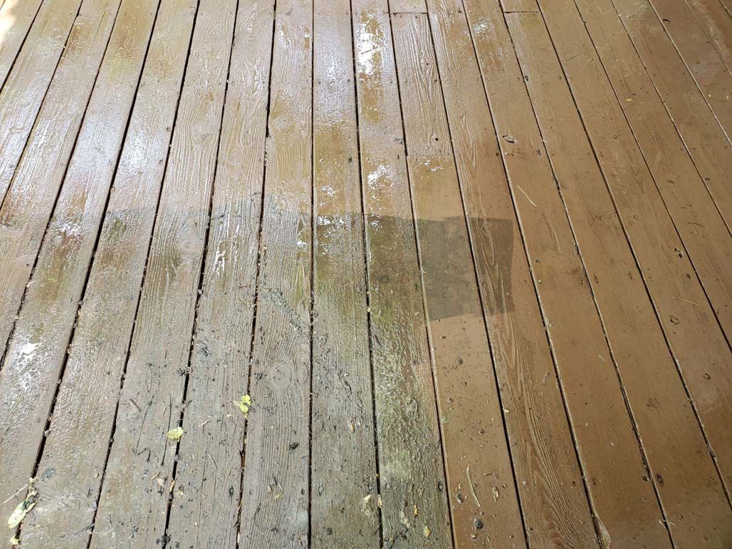 Weathered wooden deck boards with a worn, stained patch in the center