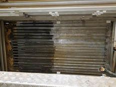 Stacked clear and black plastic tubes or rods stored on a shelf in a workshop.