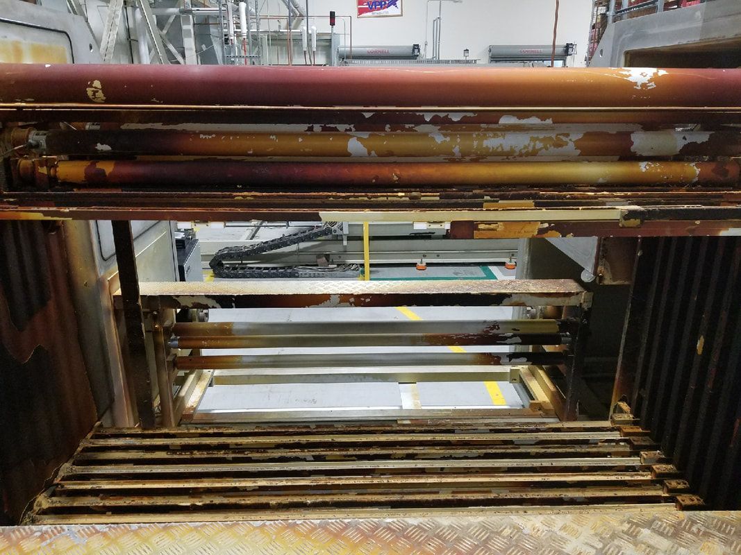 Rusty metal beams and beams stacked inside a storage rack or industrial machine frame.