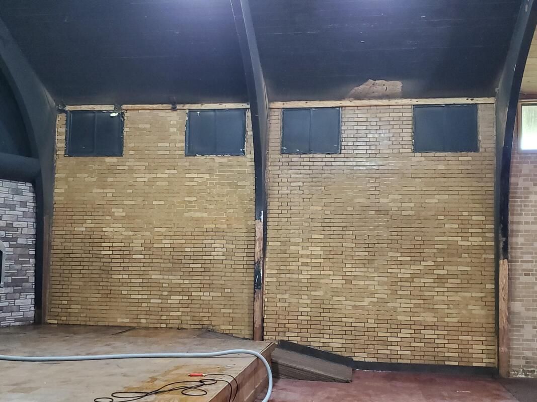 Brick wall with four small windows in an industrial interior under a dark ceiling