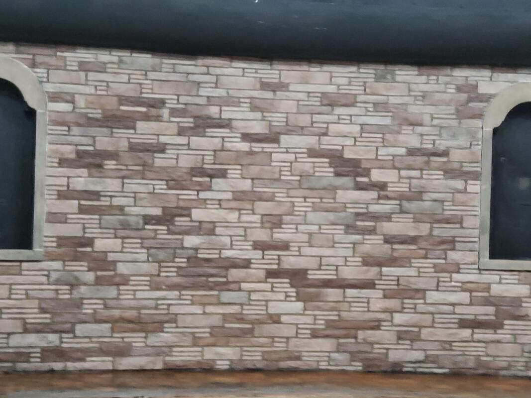 Stone and brick exterior wall with two arched window openings on either side.