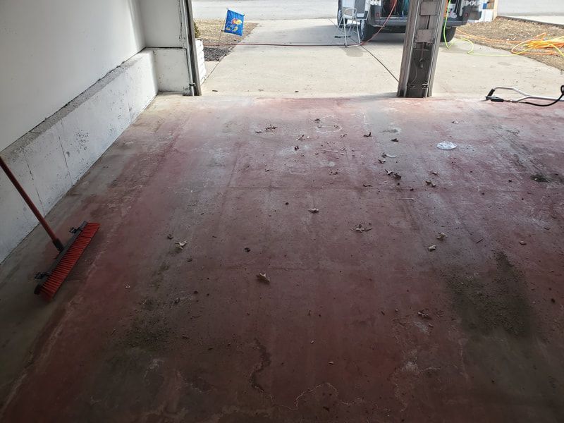 Red concrete walkway inside a building, with debris and construction materials along the edges.