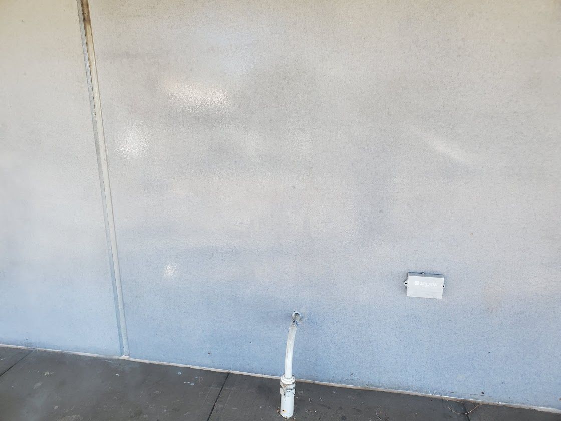 Bare light gray wall and dark floor with a small pipe near the bottom center.