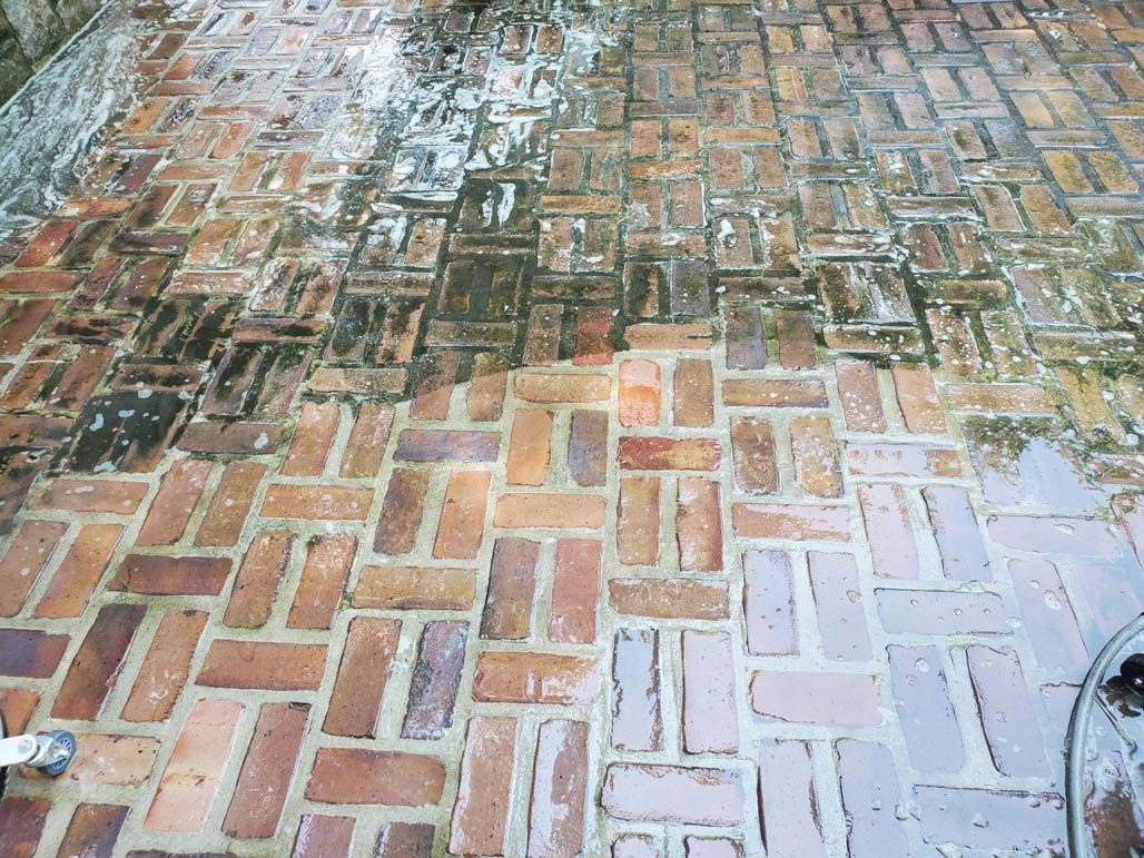 Brick walkway with wet patches and a faint reflection of trees and sky