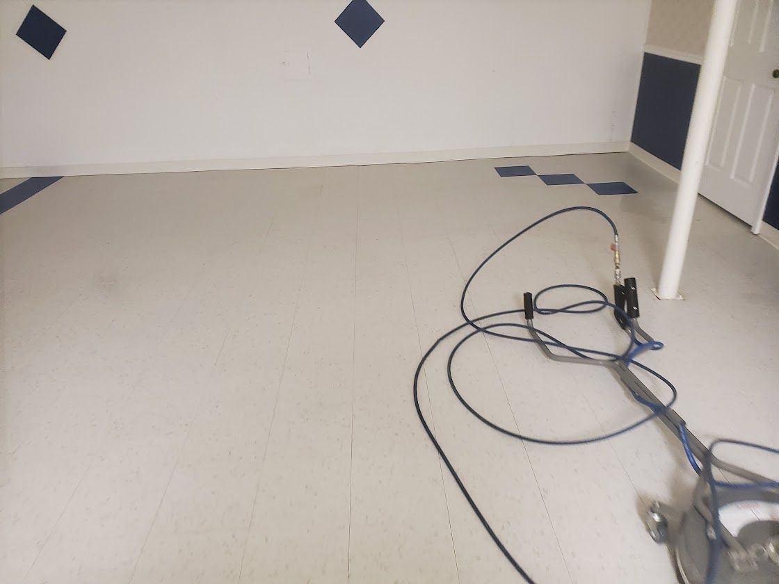 Empty room with beige floor, white walls, blue diamond accents, and cables on the floor near a doorway